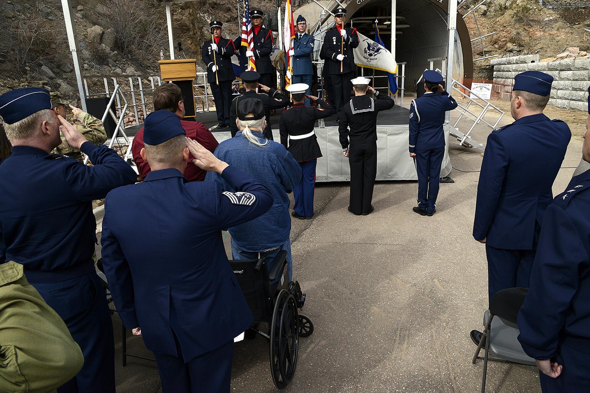 Attendees of the 50th anniversary rededication ceremony pay respect during the U.S. and Canadian national anthems at Cheyenne Mountain Air Force Station, Colo., April 15, 2016. After nearly five years of construction, Cheyenne Mountain AFS was declared fully operational April 20, 1966. Cheyenne Mountain AFS is owned by the 21st Space Wing at Peterson Air Force Base, Colo., and operated by the 721st Mission Support Group. (U.S. Air Force photo/Rob Bussard)