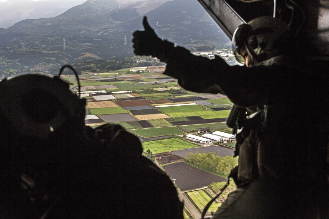 A Marine Corps crew chief gives a thumbs-up for an MV-22 Osprey aircraft to land at Japanese Camp Takayubaru, Japan, April 18, 2016. Marine Corps photo by Cpl. Nathan Wicks