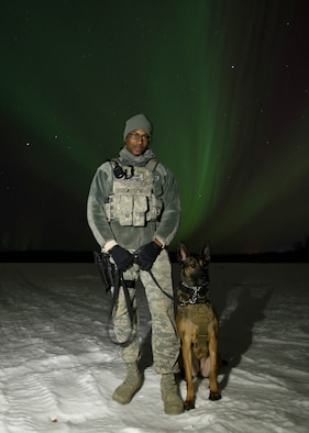 U.S. Staff Sgt. Mathis Williams, a 354th Security Forces military working dog (MWD) handler, takes a break from a patrol with MWD Oopal in the dark at 30 degrees below zero March 7, 2016, at Eielson Air Force Base, Alaska, while the aurora borealis dances behind them. Military working dogs from Eielson work alongside the human defenders who stand “Ready to go at 50 below” 24 hours a day protecting assets at the top of the world in the U.S. Air Force’s Pacific theater of operations. (U.S. Air Force photo by Staff Sgt. Shawn Nickel/Released)