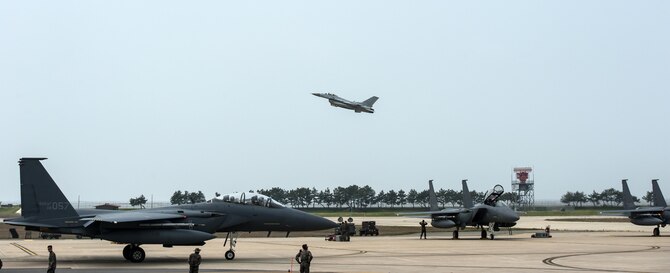 Republic of Korea air force F-15Ks from the 11th Fighter Wing, Daegu Air Base, ROK, prepare for flight as a KF-16 from the 20th Fighter Wing, Seosan Air Base, ROK takes off on the runway during Max Thunder 16 at Kunsan Air Base, Republic of Korea, April 18, 2016. Exercise Max Thunder is part of a continuous exercise program to enhance interoperability between U.S. and ROK forces. (U.S. Air Force photo by Staff Sgt. Nick Wilson/Released)