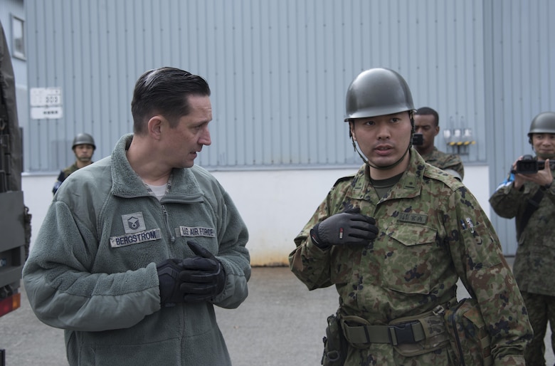 U.S. Air Force Master Sgt. Christopher Bergstrom (left), 374th Logistics Readiness Squadron air transportation specialist, speaks to a Japan Ground Self-Defense Force member at Chitose, Hokkaido, Japan, April 18, 2016. The 374th Airlift Wing airlifted vehicles and personnel to the island of Kyushu after it was struck by a devastating earthquake. (U.S. Air Force photo by Staff Sgt. Michael Washburn/Released)
