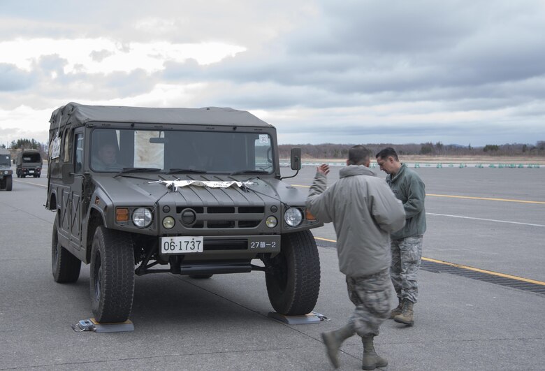 U.S. Air Force Staff Sgt. Joshua McDonald, 374th Logistics Readiness Squadron air transportation specialist, signals to Staff Sgt. Macer Allen, 374 LRS air transportation specialist, to move a vehicle forward at Chitose, Hokkaido, Japan, April 18, 2016. After the island of Kyushu was struck by a devastating earthquake, the Government of Japan requested U.S. Forces Japan to assist in the transportation of relief personnel and equipment. (U.S. Air Force photo by Staff Sgt. Michael Washburn/Released)