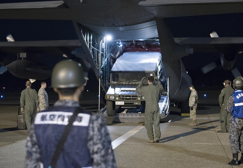 U.S. Air Force Senior Airman Dustin Brown, 36th Airlift Squadron loadmaster, marshals a Japan Ground Self-Defense Force vehicle out of a C-130 Hercules while Japan Air Self-Defense Force members look on at Kumamoto Prefecture, Japan, April 18, 2016. Yokota Air Base assisted the Government of Japan by airlifting vehicles and personnel from Hokkaido to Kumamoto Prefecture in response to recent earthquakes. (U.S. Air Force photo by Staff Sgt. Michael Washburn/Released)
