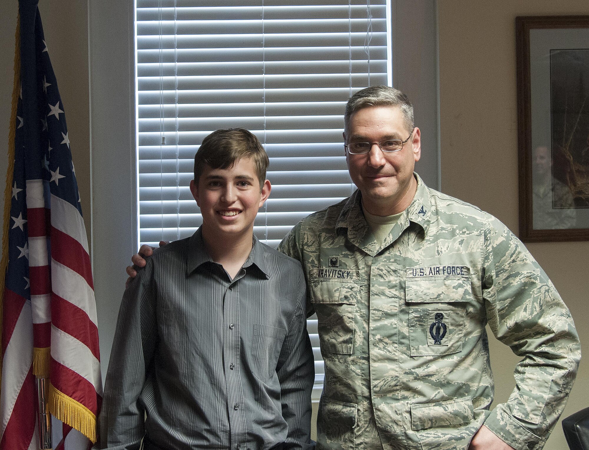 Col. Stephen Kravitsky, 90th Missile Wing commander, poses for a photo with James Gay, 16, a former F.E. Warren Commissary employee, April 12, 2016, on F.E. Warren Air Force Base, Wyo. Kravitsky presented Gay with a commander's coin for saving the life of a co-worker when he worked in the commissary. (U.S. Air Force photo by Senior Airman Jason Wiese)