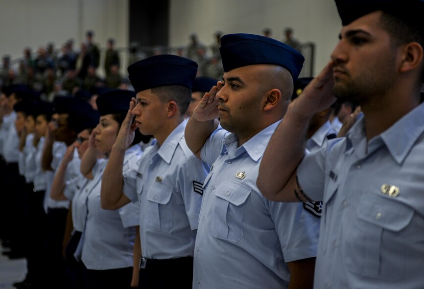 Airmen from the 57th group salute as the national anthem is played at the 57th Change of Command at Nellis Air Force Base, Nev., April 16, 2016. The 57th WG oversees the dynamic and challenging flying operations at Nellis Air Force Base and conducts advanced aircrew, cyber, cyber-space, logistics, command and control training through the U.S. Air Force Weapons School, Red Flag and Green Flag exercises. (U.S. Air Force photo by Airman 1st Class Kevin Tanenbaum)