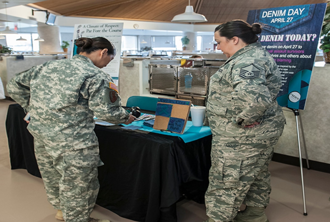 COLUMBUS, Ohio (April 6, 2016) Air Force Master Sgt. Maggie Ladd (right) discusses the symbolism of fabric squares to Army Capt. Miracle Garcia at an information fair for Sexual Assault Awareness and Prevention Month. The squares are worn to show support for sexual assault survivors during "Denim Day" on April 27.