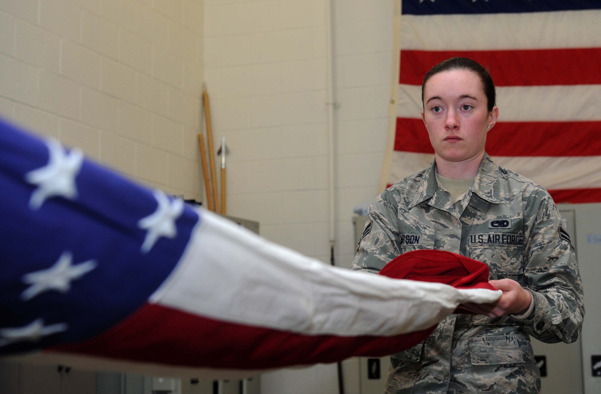 Airman 1st Class Lauren Watson, 22nd Force Support Squadron honor guardsman, practices a two-man flag fold, April 13, 2016, at McConnell Air Force Base, Kansas. Watson was one of eight members to be formally instated into the base honor guard program through an officially induction ceremony. (U.S. Air Force photo by Senior Airman Tara Fadenrecht)