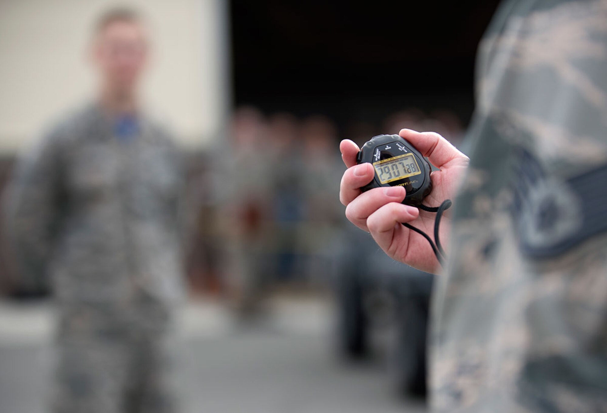 An evaluator uses a stop-watch to time how long it takes for one team member to finish a task during the first quarter load crew competition at Joint Base Elmendorf-Richardson, Alaska, April 15, 2016. (U.S. Air Force photo by Staff Sgt. Sheila deVera)
