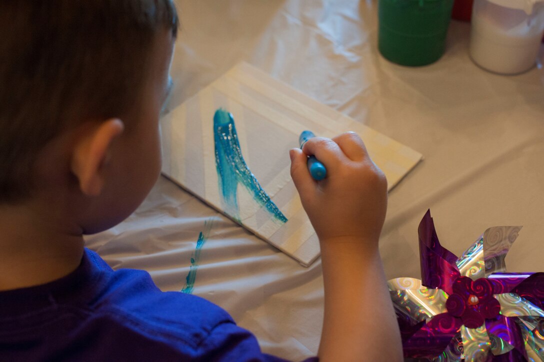 David, a Family Child Care member, paints a canvas during a craft fair for Month of the Military Child at Liberty Park Housing Office April 16, 2015. The craft fair was coordinated by Joint Base Andrews Family Child Care for MOTMC, a time to honor military youth for the important role they play contributing to the strength of the military family. (U.S. Air Force photo by Airman 1st Class Rustie Kramer/Released)