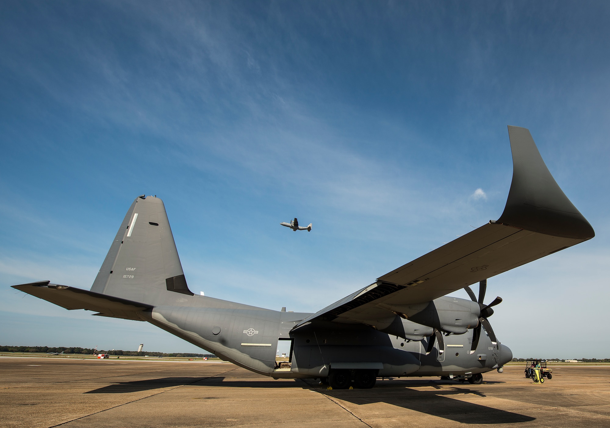 A modified MC-130J waits for its next mission as another C-130 lifts off above it at Eglin Air Force Base, Fla. The test aircraft has been fitted with vertical fins on each wing, called winglets.  The 413th Flight Test Squadron aircrew and engineers tested the modified aircraft over eight flights.  The goal of the tests was to collect data on possible fuel efficiency improvements and performance with the winglets and lift distribution control system installed.  (U.S. Air Force photo/Samuel King Jr.)