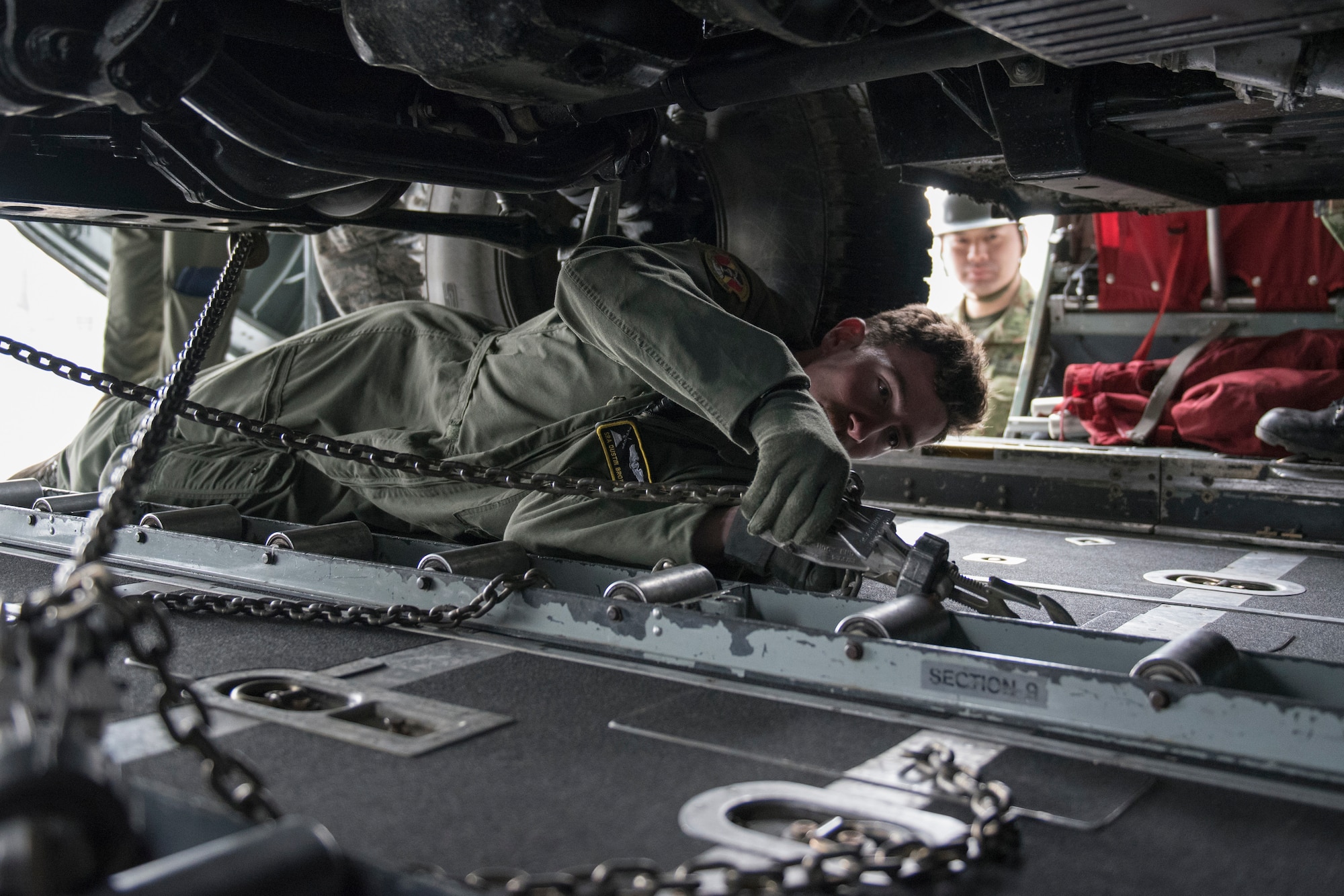 Senior Airman Dustin Brown, 36th Airlift Squadron loadmaster, uses chains to strap down a Japan Ground Self-Defense Force vehicle into a C-130 Hercules at Chitose, Hokkaido, Japan, April 18, 2016. Before the vehicles could board the C-130s they needed to be inspected to ensure they were suitable for flight. The vehicles were later dropped off at Kumamoto Prefecture, Japan, the epicenter of recent earthquake. (U.S. Air Force photo by Staff Sgt. Michael Washburn/Released)