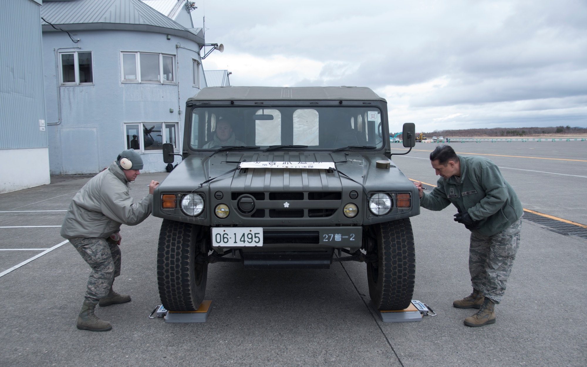 (Left) Senior Airman Brandon Ihnat and Master Sgt. Christopher Bergstrom, both 374th Logistics Readiness Squadron Combat Mobility Flight air transportation specialists, write the weight of a Japan Ground Self-Defense Force vehicle on duct tape at Chitose, Hokkaido, Japan, April 18, 2016. The vehicles needed to be weighed to ensure safe passage aboard the C-130. These vehicles, along with JGSDF members, were being airlifted to Kumamoto prefecture to assist with disaster relief efforts after Japan was struck by series of earthquakes. (U.S. Air Force photo by Staff Sgt. Michael Washburn/Released)