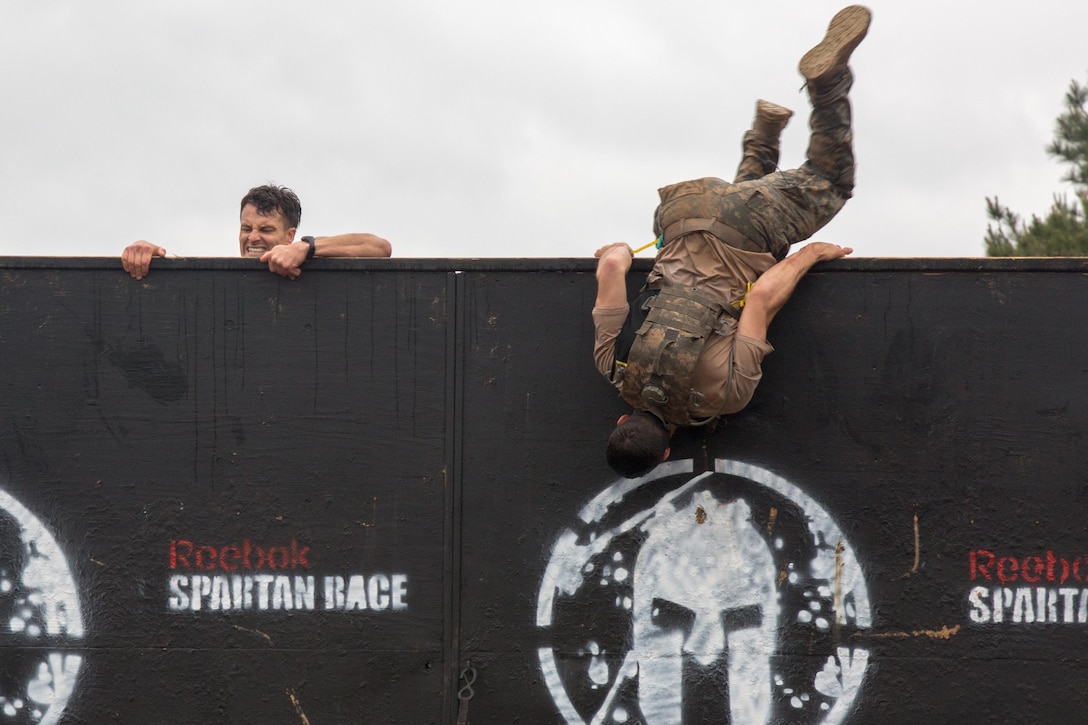 Army Capt. Dave Mathews and 1st Lt. Colton Barber climb over an 8-foot wall on the Spartan Race course at Fort Mitchell, Ala., April 16, 2016, during the 33rd annual Best Ranger Competition. The three-day competition comprised challenges testing competitors' physical, mental and technical capabilities. Army photo by Staff Sgt. Brian Kohl