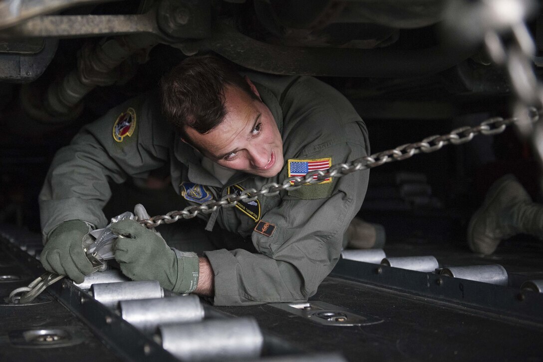 Air Force Staff Sgt. Andrew Thompson uses a chain to strap down a Japanese army vehicle in a C-130 Hercules aircraft in Chitose, Japan, April 18, 2016. Two C-130 Hercules picked up four vehicles and eight Japanese soldiers and flew them to the island of Kyushu to assist in disaster relief operations following a series of earthquakes that struck Japan. Thompson is a loadmaster assigned to the 36th Airlift Squadron. Air Force photo by Staff Sgt. Michael Washburn