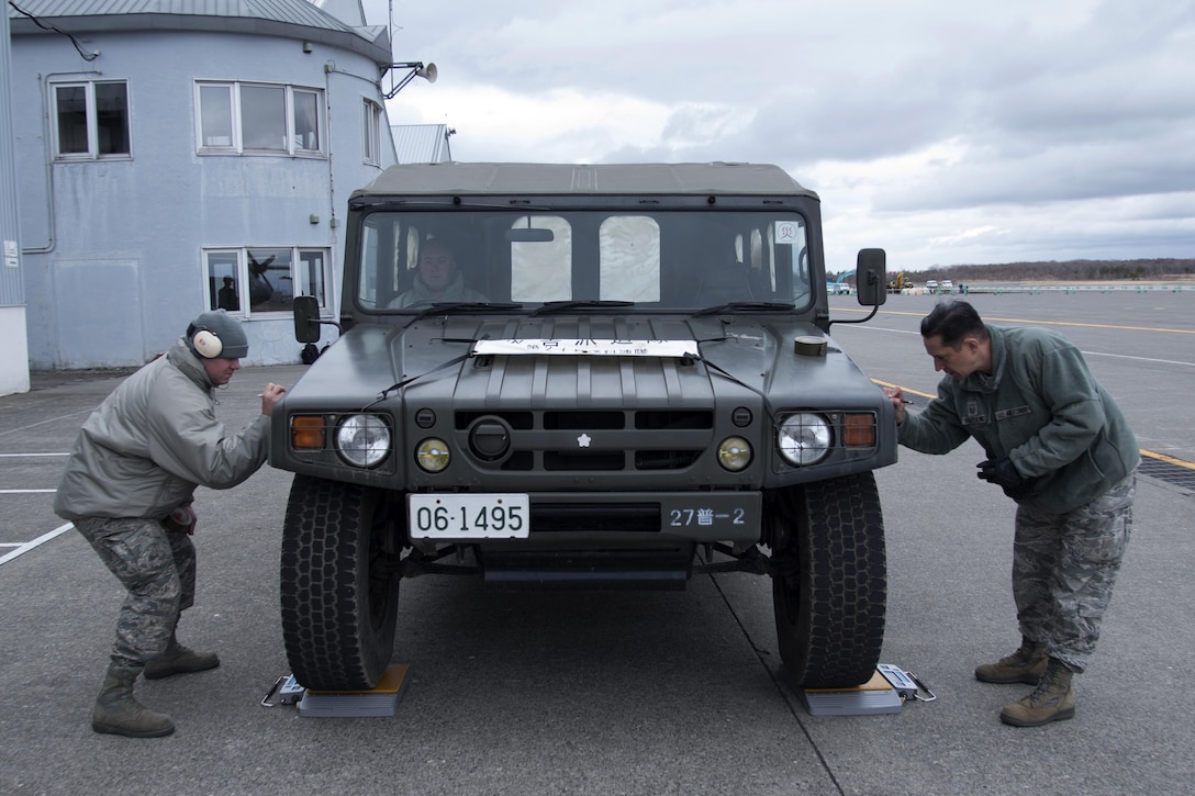 Air Force Senior Airman Brandon Ihnat, left, and Master Sgt. Christopher Bergstrom write the weight of a Japanese army vehicle on duct tape in Chitose, Japan, April 18, 2016. The vehicles needed to be weighed to ensure safe passage aboard a C-130 Hercules aircraft. Ihnat and Bergstrom are air transportation specialists assigned to the 374th Logistics Readiness Squadron. Air Force photo by Staff Sgt. Michael Washburn