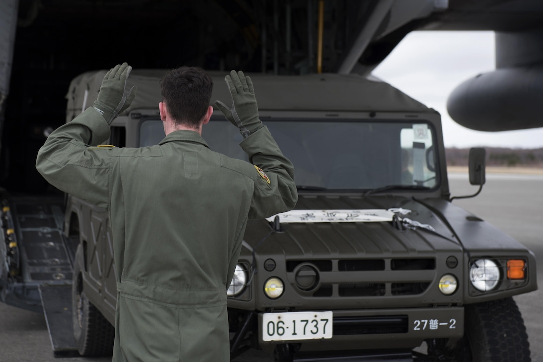 Air Force Senior Airman Dustin Brown marshals a Japanese army vehicle into a C-130 Hercules aircraft in Chitose, Japan, April 18, 2016. Brown is a loadmaster assigned to the 36th Airlift Squadron. Air Force photo by Staff Sgt. Michael Washburn