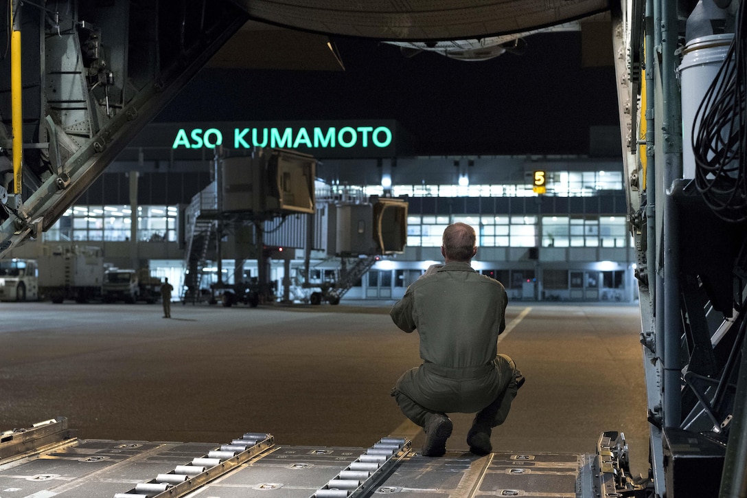 Air Force Master Sgt. Ryan Atkinson looks out the back of a C-130 Hercules aircraft after dropping off two Japanese army vehicles and four Japanese soldiers in Kumamoto prefecture, Japan, April 18, 2016. Atkinson is a loadmaster assigned to the 36th Airlift Squadron. Air Force photo by Staff Sgt. Michael Washburn