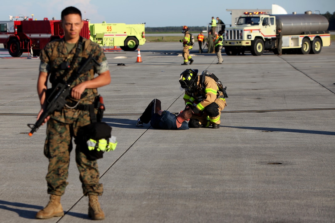 A Marine with the Provost Marshal’s Office establishes a perimeter while a firefighter tends to a simulated casualty during a Mass Casualty Exercise on Marine Corps Air Station Cherry Point, N.C., April 7, 2016.  The exercise was designed to simulate the response if an emergency were to occur. Annually, the air station is required to have exercises to ensure protocol and safety standards are met for potential emergencies. On years the biannual air show occurs, the training revolves around scenarios specific to that kind of event. (U.S. Marine Corps photo by Cpl. Jason Jimenez/Released)
