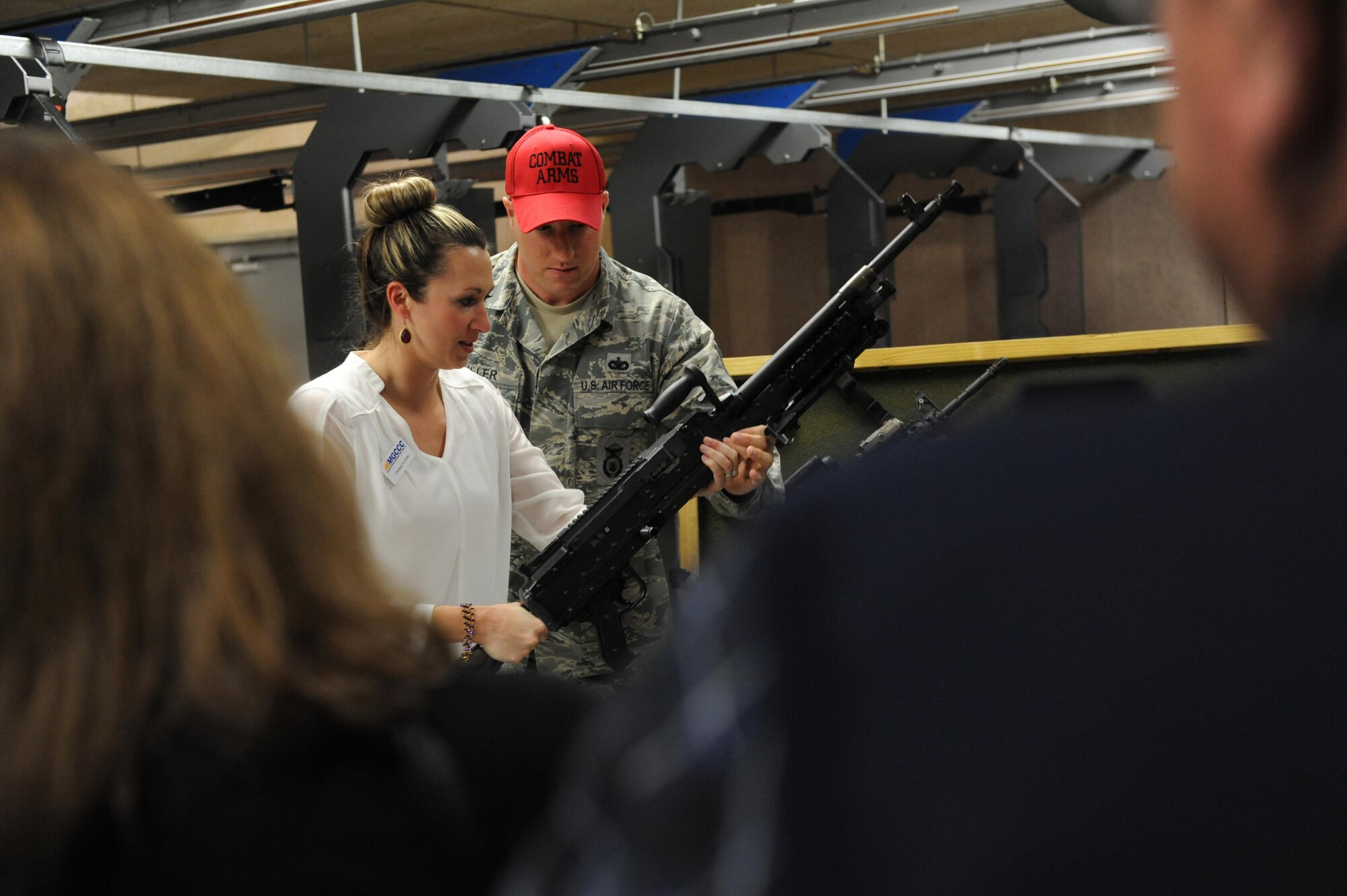Staff Sgt. Jared Miller, 81st Security Forces Squadron combat arms instructor, hands Christen Duhe, Mississippi Gulf Coast Community College Jefferson Davis Campus business development and hospitality resort management center director, a M240B machine gun at the 81st SFS combat arms training and maintenance building during an honorary commanders 81st Mission Support Group orientation tour April 14, 2016, Keesler Air Force Base, Miss. The honorary commander program is a yearly partnership between base leadership and local civic leaders to promote strong ties between military and civilian leaders. (U.S. Air Force photo by Kemberly Groue)