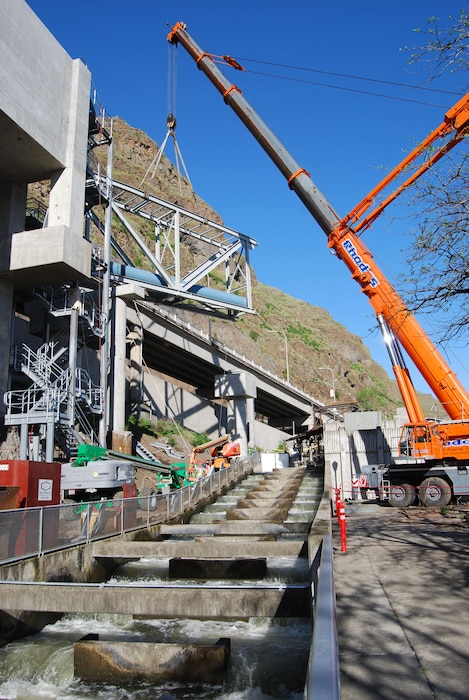 Contractors use large cranes to hoist heavy loads over the top of Lower Granite Lock and Dam’s visitor center and adult fish ladder as they construct a new juvenile fish bypass system leading from the dam to the Juvenile Fish Facility. The fishway improvements are an important part of the Corps’ mission to save salmon and other endangered or threatened species. 