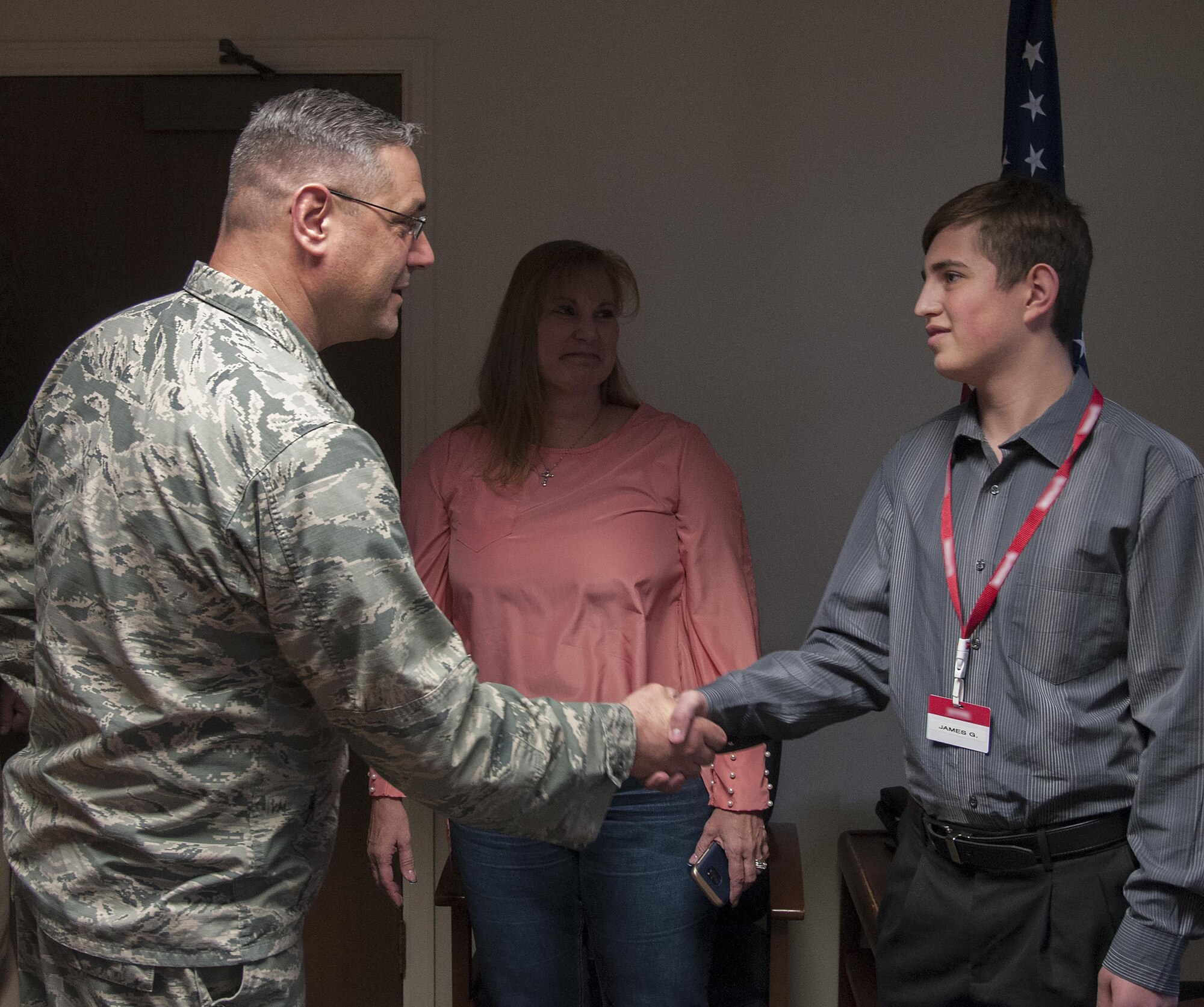 In this photo illustration, Col. Stephen Kravitsky, 90th Missile Wing commander, shakes hands with James Gay, 16, a former F.E. Warren Commissary employee, April 12, 2016, on F.E. Warren Air Force Base, Wyo. Gay saved the life of a co-worker who suffered heart troubles on the job while Gay still worked at the commissary. (U.S. Air Force photo illustration by Senior Airman Jason Wiese)