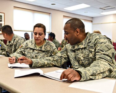 Staff Sgt. Marisol McKinley, left, Paralegal, and Sgt. Ronnie Payne, right, Human Resources Sergeant work together on applying the competencies of Master Resiliency Training. MRT is taught yearly to help soldiers better handle stress. 
(Photo by Sgt. Aaron Berogan)