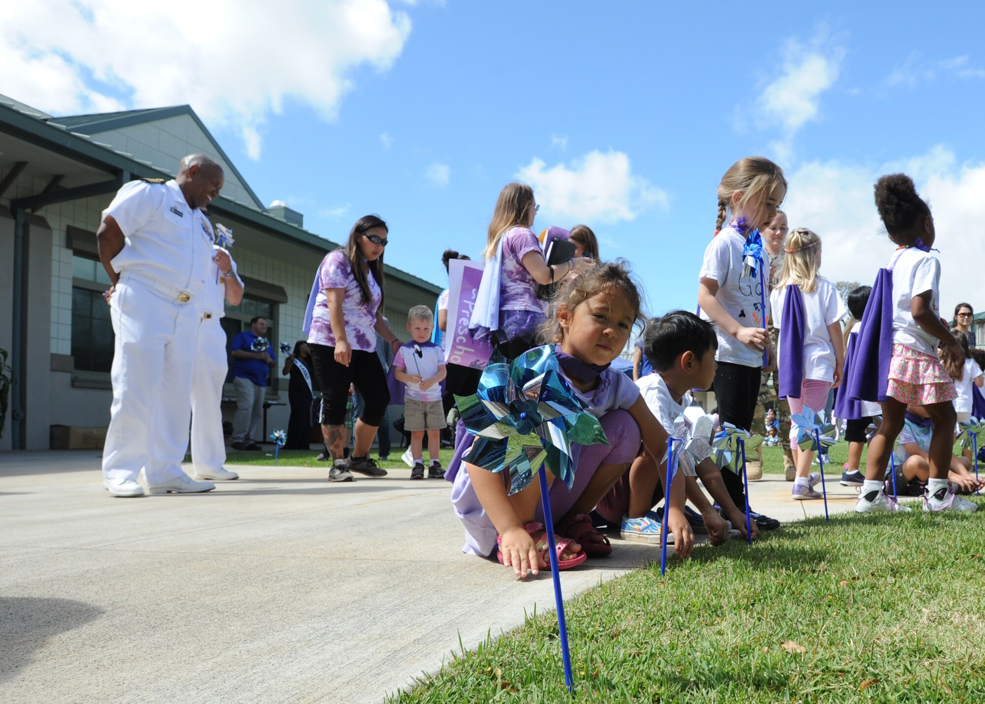 Captain Stanley Keeve, Jr., commander Joint Base Pearl-Harbor Hickam and Command Master Chief Jack Johnson, Joint Base Pearl-Harbor Hickam watches as students plant pinwheels at the Center Drive Child Development Center on Joint Base Pearl-Harbor Hickam, Hawaii, April 15, 2016. Children, parents and leadership took part in activities on the playgrounds at the CDC in celebration of the Month of the Military Child and planted pinwheels in honor of Child Abuse Prevention Month. (U.S. Air Force photo by Capt. Nicole White/Released)
