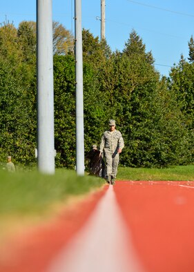 Senior Airman Jacob Coppola, 436th Logistics Readiness Squadron fuel controller, picks up trash along the base track during a spring cleanup event April 18, 2016, at Dover Air Force Base, Del. More than 40 Airmen were split into five teams to help collect trash, pick weeds and clean up outside common areas. (U.S. Air Force photo/Senior Airman William Johnson)