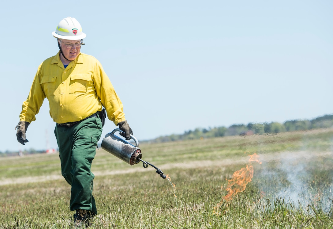 As part of a controlled burn, a member of the Virginia Department of Forestry ignites a fire with a drip torch at Langley Air Force Base, Va., April 17, 2016. Drip torches use a mixture of gasoline and diesel fuel to create the consistency needed for controlled burns. (U.S. Air Force photo by Senior Airman Kayla Newman)