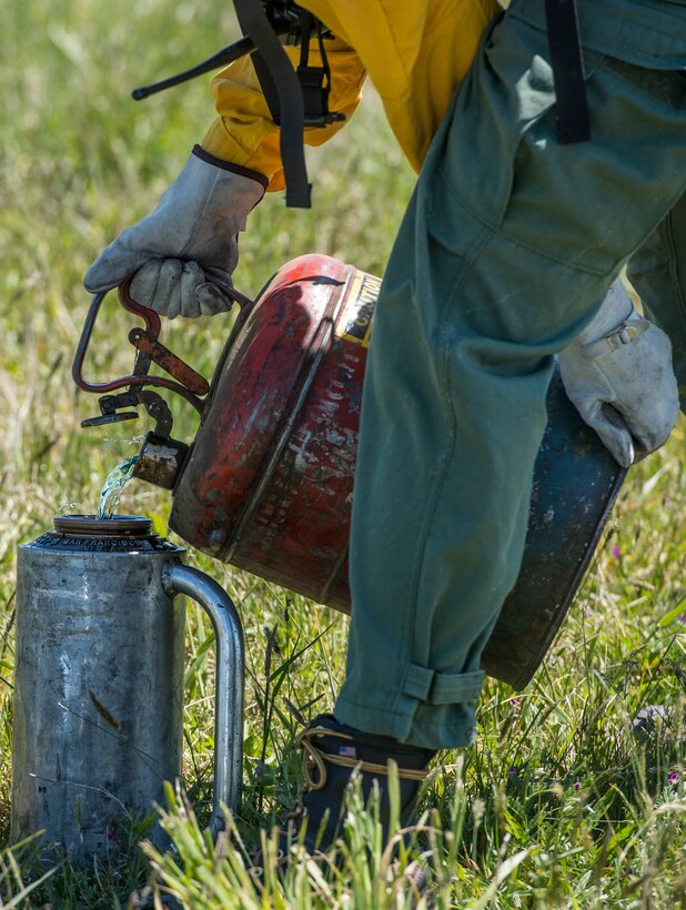 A member of the Virginia Department of Forestry pours fuel into a drip torch at Langley Air Force Base, Va., April 17, 2016. The Department of Forestry partnered with the 633rd Civil Engineer Squadron fire department to burn a field prior to a fireworks show. (U.S. Air Force photo by Senior Airman Kayla Newman)