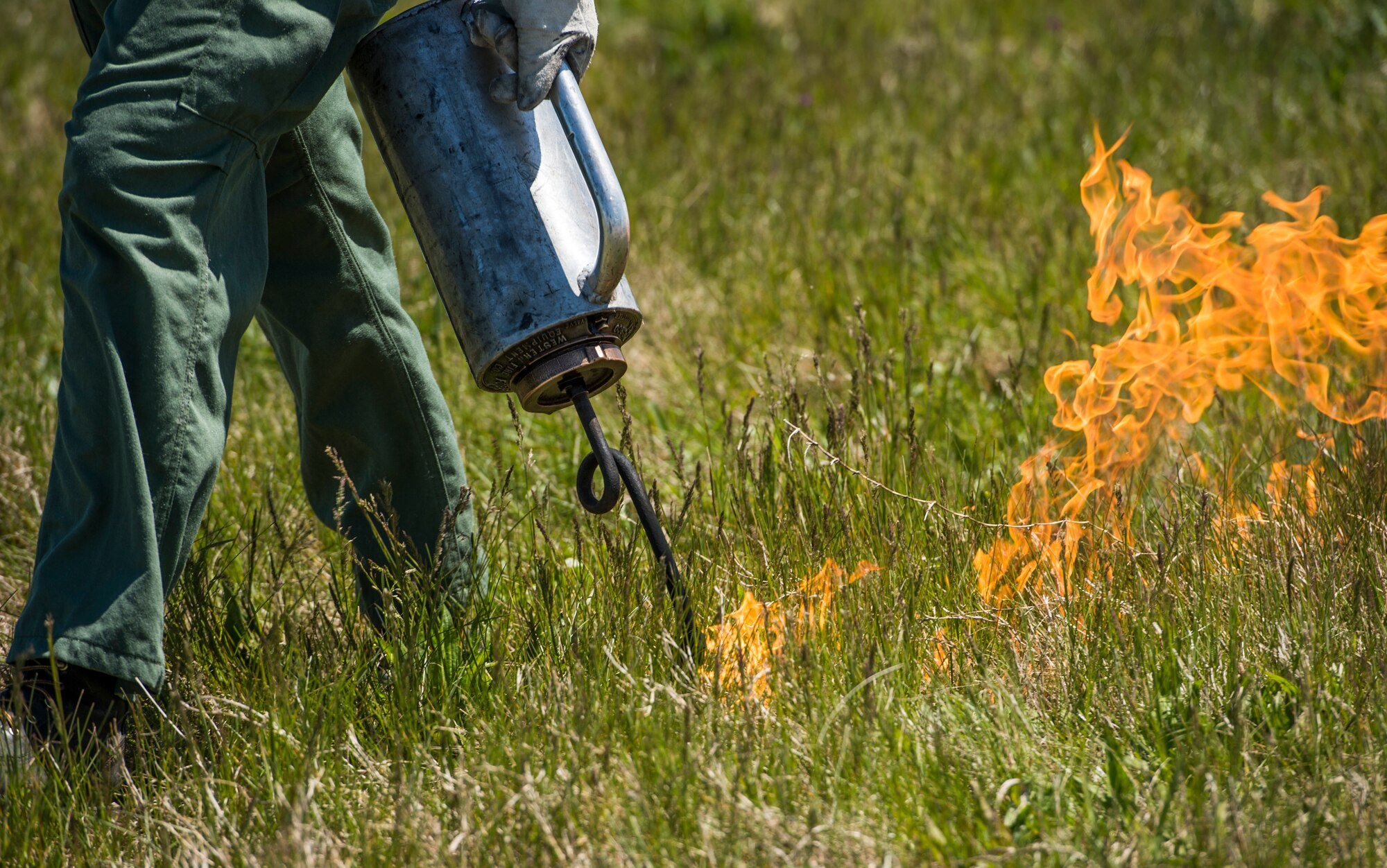 A member of the Virginia Department of Forestry uses a drip torch to conduct a controlled burn at Langley Air Force Base, Va., April 17, 2016. Certified technicians burned grass and vegetation that had grown on the flight line infield in preparation for the AirPower over Hampton Roads Open House fireworks display. (U.S. Air Force photo by Senior Airman Kayla Newman)