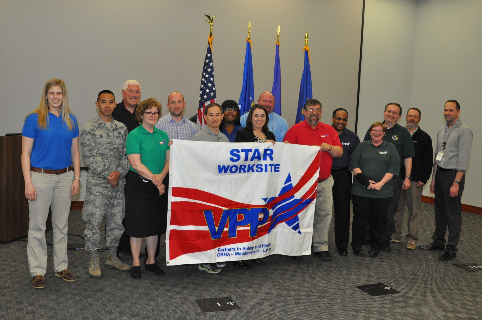 Employees and management officials from the Air Force Research Laboratory Sensors Directorate, along with Occupational Safety and Health Administration officials, display OSHA’s Voluntary Protection Program Star Site banner during an April 14 ceremony recognizing the Sensors Directorate as just the 56th certified VPP Star site in the DOD. (U.S. Air Force photo/Bryan Ripple)