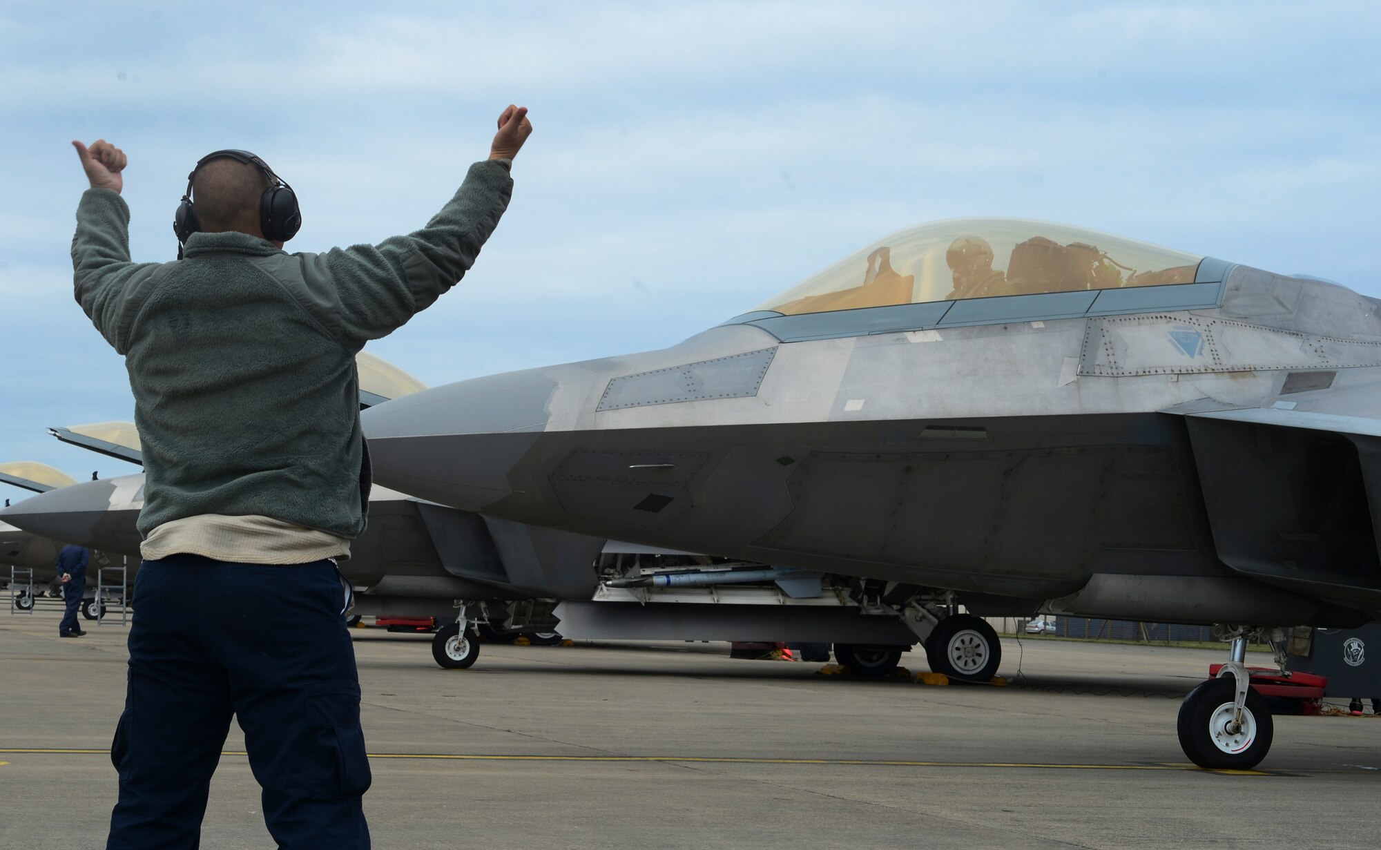 A maintainer assigned to the 325th Maintenance Squadron marshals an F-22 from the 95th Fighter Squadron, Tyndall Air Force Base, Fla., before takeoff from Royal Air Force Lakenheath, England, April 18, 2016. The 5th generation, multi-role fighter aircraft is deployed here to maximize training opportunities, affirm enduring commitments to NATO allies, and deter any actions that destabilize regional security. (U.S. Air Force photo by Senior Airman Dawn M. Weber/Released)