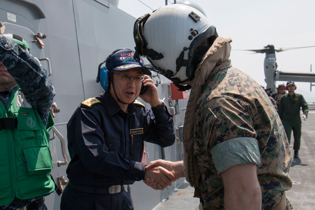 Japan Maritime Self-Defense Force Rear Adm. Koji Manabe, center left, greets a senior Marine Corps officer aboard the JS Hyuga near Kumamoto, Japan, April 19, 2016. The Marine is assigned to the 31st Marine Expeditionary Unit. Navy photo by Petty Officer 3rd Class Gabriel B. Kotico
