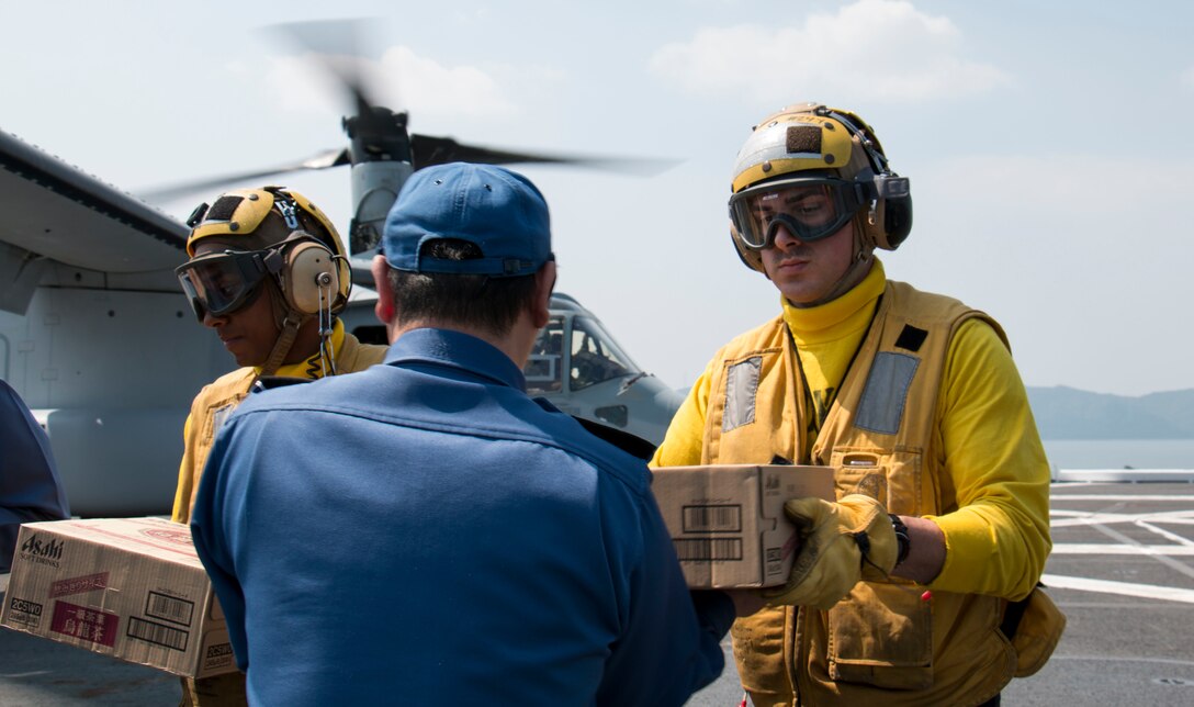 U.S. Navy Petty Officer 3rd Class Ryan Moats, left, and Seaman Connor Brady, right, help Japan Maritime Self-Defense Force members load earthquake relief supplies onto a U.S. Marine Corps MV-22B Osprey aircraft aboard the JS Hyuga near Kumamoto, Japan, April 19, 2016. Moats and Brady are assigned to the 31st Marine Expeditionary Unit. Navy photo by Petty Officer 3rd Class Gabriel B. Kotico