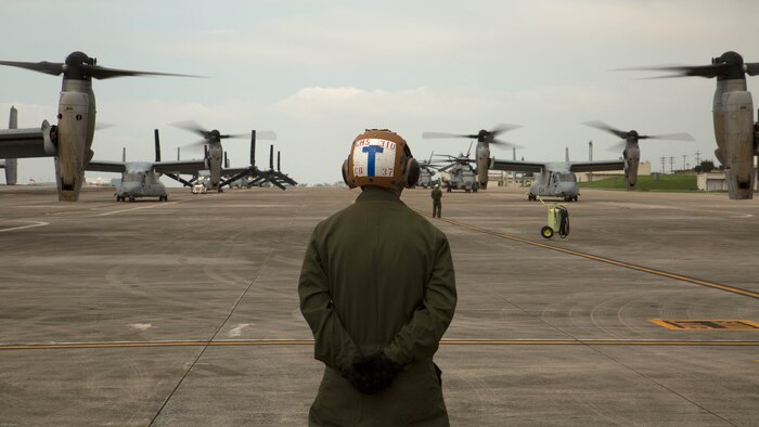 A Marine waits to guide MV-22 Ospreys with Marine Medium Tiltrotor Squadron 265, 31st Marine Expeditionary Unit, during their takeoff April 17 on Marine Corps Air Station Futenma. United States Forces, Japan is providing operational airlift support in coordination with the Government of Japan’s efforts to provide relief following the devastating earthquake near Kumamoto. 