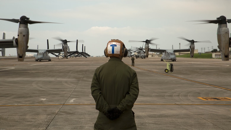 A Marine waits to guide MV-22 Ospreys with Marine Medium Tiltrotor Squadron 265, 31st Marine Expeditionary Unit, during their takeoff April 17 on Marine Corps Air Station Futenma. United States Forces, Japan is providing operational airlift support in coordination with the Government of Japan’s efforts to provide relief following the devastating earthquake near Kumamoto. 