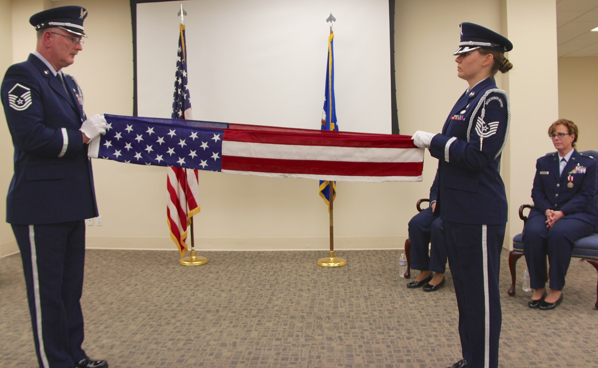 932nd Honor Guard team members prepare to fold an American flag and present it to Lt. Col Kelly Compas (seated at right) during her retirement ceremony held on April 6.  She was also presented with a shadow box representing her many years of service with the 932nd Medical Group, an Air Force Reserve Command unit located in Illinois.  (U.S. Air Force photo by Maj. Stan Paregien)