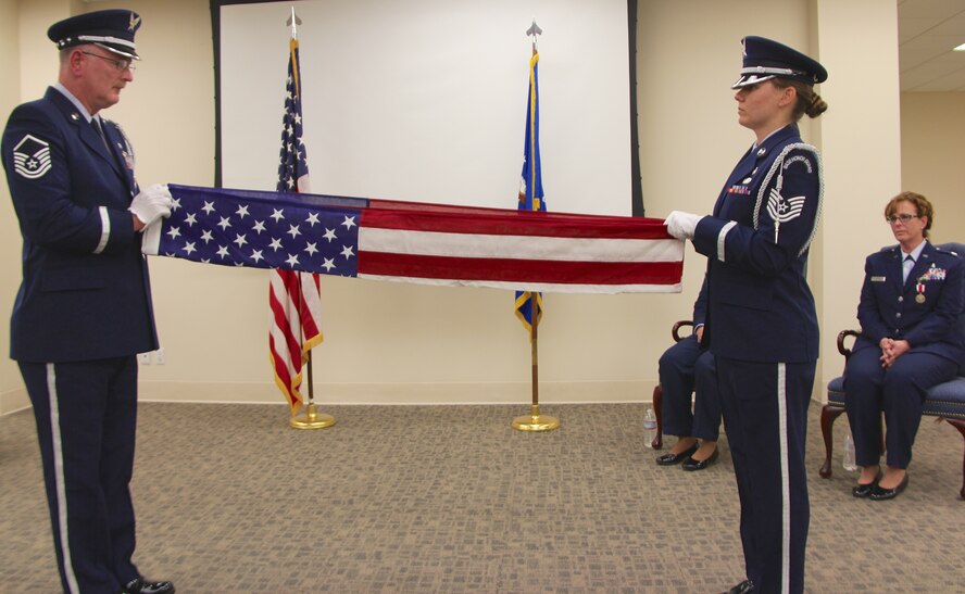 932nd Honor Guard team members prepare to fold an American flag and present it to Lt. Col Kelly Compas (seated at right) during her retirement ceremony held on April 6.  She was also presented with a shadow box representing her many years of service with the 932nd Medical Group, an Air Force Reserve Command unit located in Illinois.  (U.S. Air Force photo by Maj. Stan Paregien)
