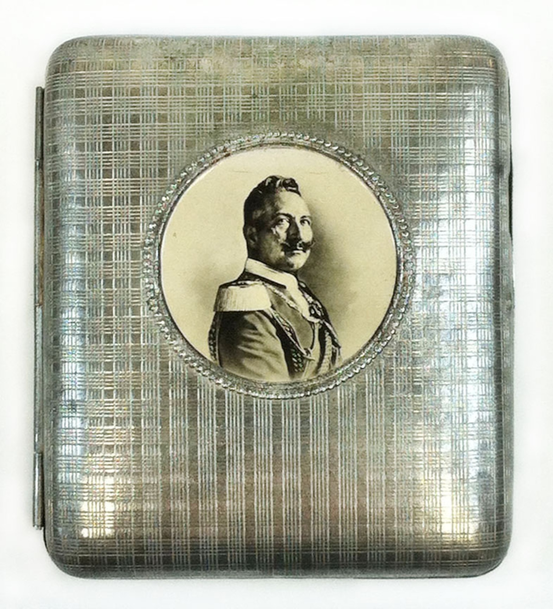 The front exterior of this metal cigarette case displays a photo of Kaiser Wilhelm II, who was the last King of Prussia. He reigned from 1888 to 1918. His great-uncle was Frederick Wilhelm IV, who in 1842 designed the pickelhaube, which became the helmet worn by the Prussian army. Capt. Edward V. Rickenbacker, America’s highest scoring ace of WWI, brought this Prussian cigarette case home as a wartime souvenir. It is unknown how he attained it.