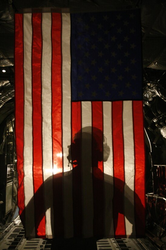 U.S. Marine Corps Corporal Jacob Hall, a crew chief with Marine Aerial Refueling Transportation Squadron 352, stands in front of an American Flag after a battlefield illumination mission aboard Camp Bastion, Afghanistan, July 18, 2014. Battlefield illumination missions were implemented to light up areas in support of nighttime coalition operations within Regional Command (Southwest). (DoD photo by Sgt. Frances Johnson, U.S. Marine Corps/Released)