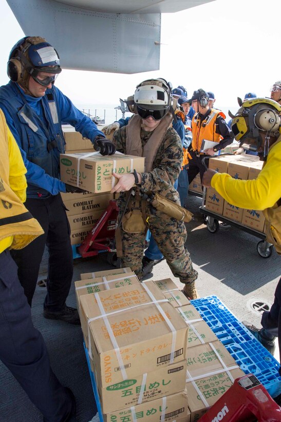 U.S. Marine Corps Sgt. Ginger Jordan, center, hands supplies to a U.S. sailor to be loaded onto a MV-22B Osprey aircraft with help from Japan Maritime Self Defense Force members aboard the JS Hyuga at sea, near Kumamoto, Japan, April 20, 2016. Jordan is a maintenance administrative specialist assigned to Marine Medium Tiltrotor Squadron 265, 31st Marine Expeditionary Unit. Marine Corps photo by Cpl. Darien J. Bjorndal