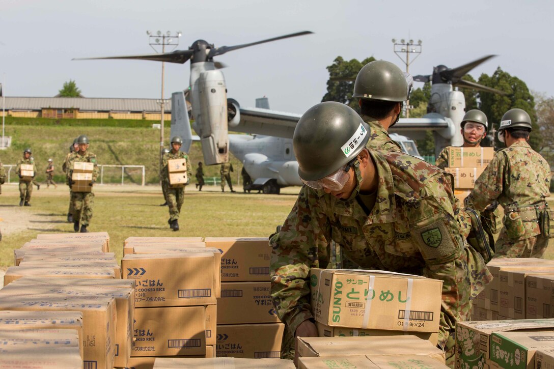 A Japanese soldier piles boxes of humanitarian aid after being off loaded from a U.S. Marine Corps MV-22B Osprey aircraft and stack the boxes at the Hakusui Sports Park, Kyushu island, Japan, April 20, 2016. Marine Corps photo by Cpl. Darien J. Bjorndal