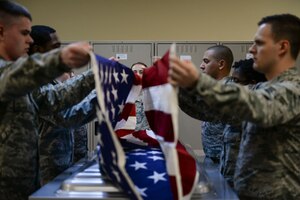 Honor guardsmen in training work with experienced members to practice properly removing a flag from a casket at Mountain Home Air Force Base, Idaho, March 3, 2016. The base honor guard does roughly 300 deatils a year, mostly consisting of funerals. (U.S. Air Force photo by Senior Airman Jessica H. Evans/RELEASED)
