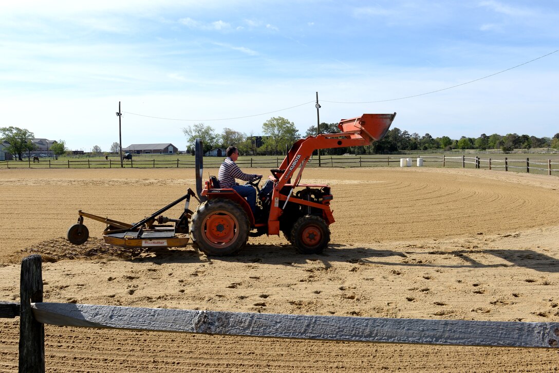 Joe Harvey, facilities manager at the Langley Saddle Club, uses a screen pulled by a tractor to smooth out the dirt in the lighted riding arena at Langley Air Force Base, Va., April 15, 2016. The farm currently has 12 horses, yet 21 stalls are available for boarding by active-duty and retired Service members. (U.S. Air Force photo by Airman 1st Class Kaylee Dubois)