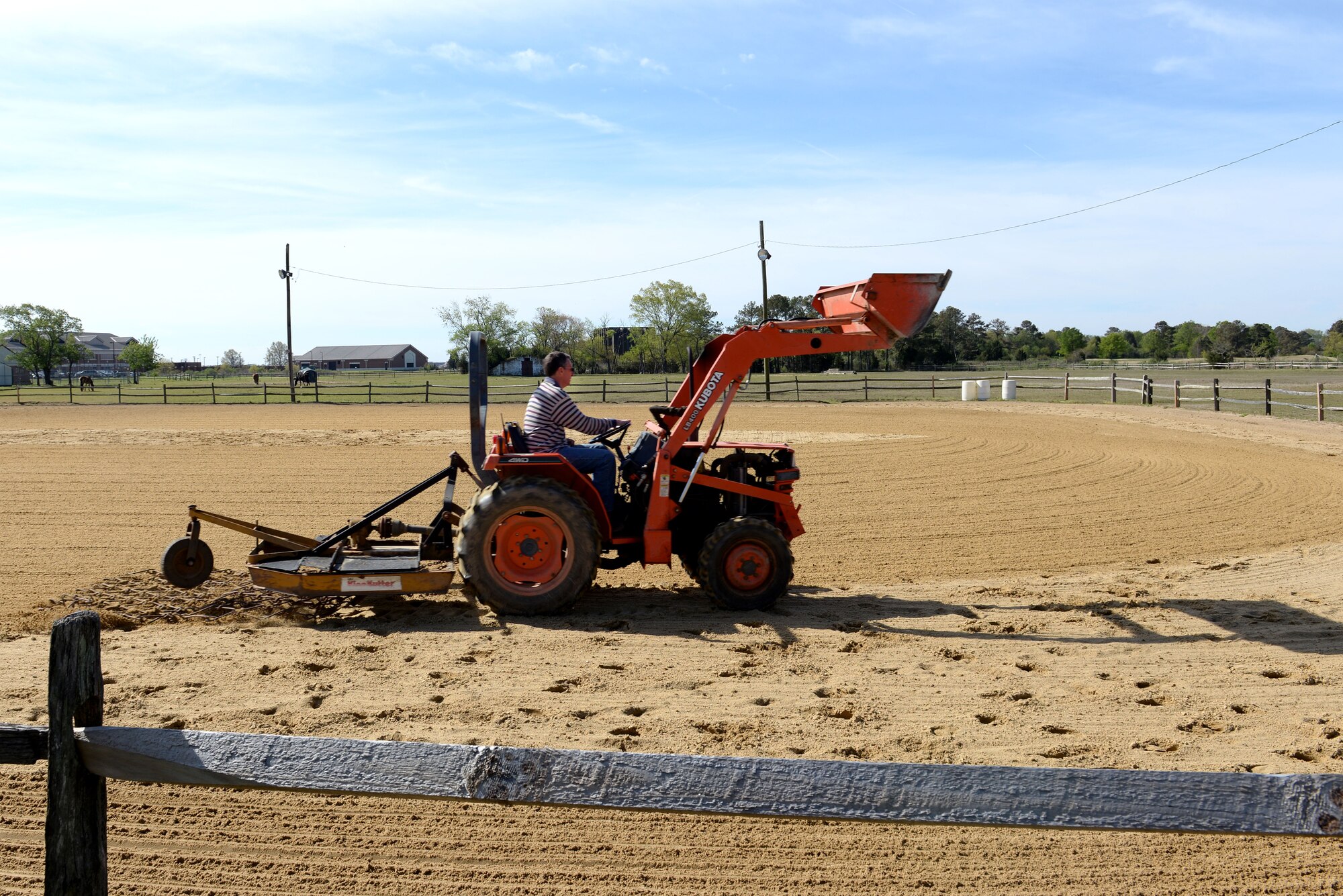 Joe Harvey, facilities manager at the Langley Saddle Club, uses a screen pulled by a tractor to smooth out the dirt in the lighted riding arena at Langley Air Force Base, Va., April 15, 2016. The farm currently has 12 horses, yet 21 stalls are available for boarding by active-duty and retired Service members. (U.S. Air Force photo by Airman 1st Class Kaylee Dubois)