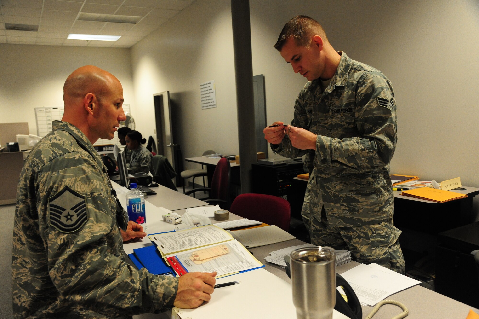 U.S. Air Force Senior Airman Aaron Hall, a 509th Force Support Squadron career development coordinator, processes deployment documents for Master Sgt. Cory McGee, the 509th Civil Engineer Squadron assistant chief of B shift, during CONSTANT VIGILANCE 16 at Whiteman Air Force Base, Mo., April 12, 2016. The exercise includes elements that test and refine Air Force Global Strike Command’s policies, training and techniques at the tactical and operational levels. (U.S. Air Force photo by Airman 1st Class Keenan Berry)