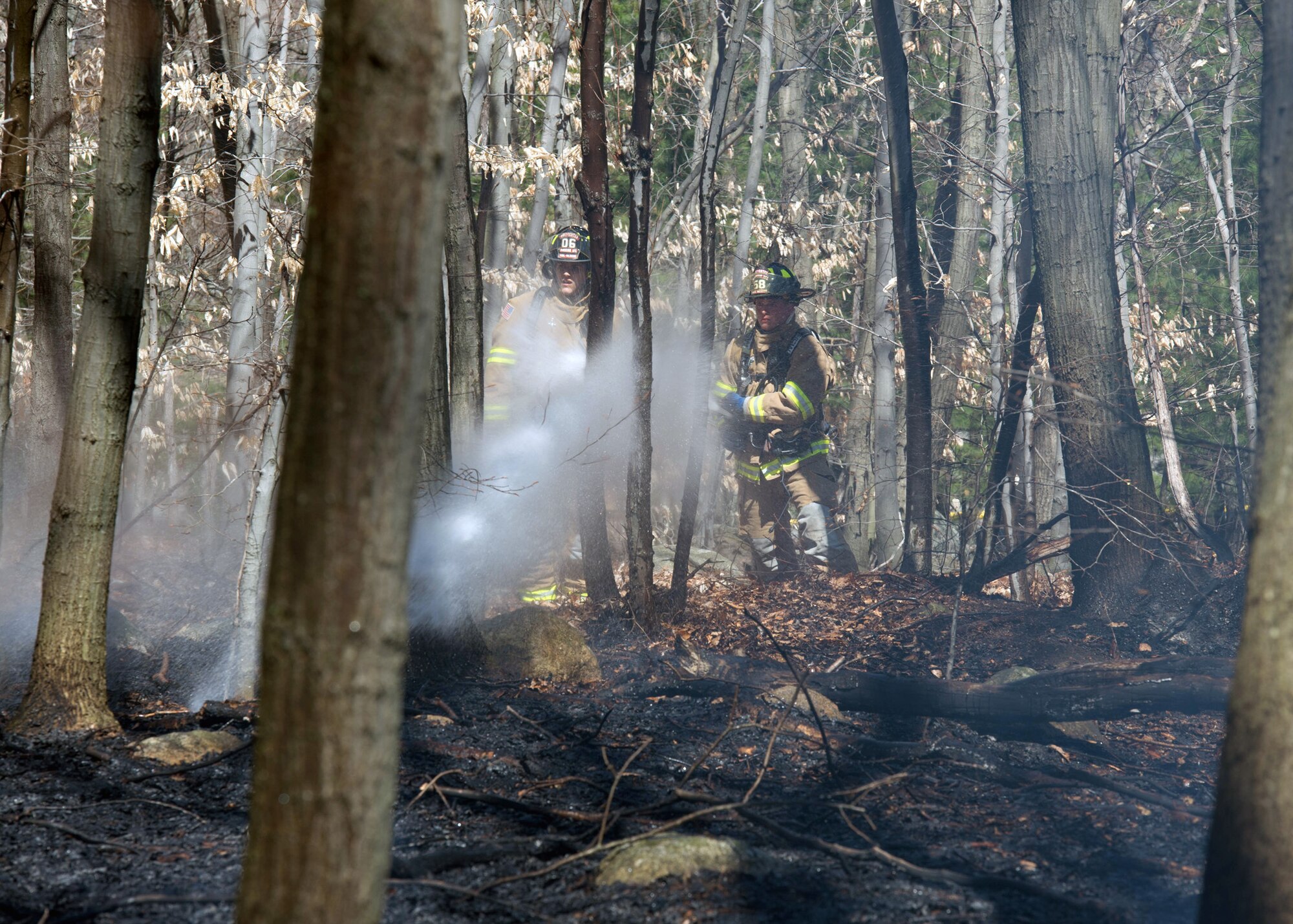 Hanscom Air Force Base firefighters, Matthew Doucet, right, and Josh Elsten, extinguish a small brush fire in the woods on base April 15. The base fire department responded to douse the fire. (U.S. Air Force photo by Jerry Saslav)