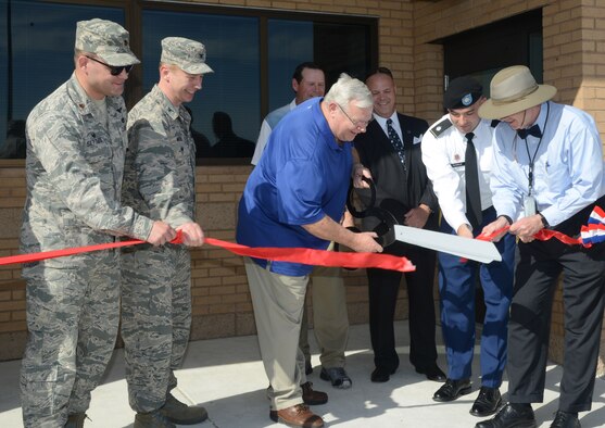 Clifford Cunningham, 412th Logistics Readiness Squadron Fuels technical advisor, cuts the red ribbon to the Bulk Fuels Storage Area. Maj. Justin Settles, Defense Logistics Agency Energy Americas-West commander; Col. Timothy Michel Individual Mobilization Augmentee to the 412th Mission Support Group Commander; Army Lt. Col. Dennis Sugrue, Army Corps of Engineers; and James Judkins, 412th Civil Engineer Group director, hold the ribbon, while Ron Fedrick, president of Nova Group, Inc., and Michael Sears, 412th Logistics Readiness Squadron director, look on. (U.S. Air Force photo by Christopher Ball.)