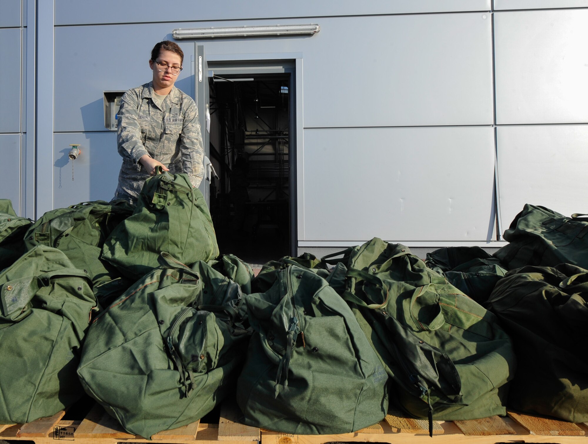 An Airman drops her chemical gear bag on a pallet after being issued individual protective equipment during Wing Thunder, April 20, at Ramstein Air Base, Germany.  The 86th Logistics Readiness Squadron processed more than 100 chemical gear bags for personnel during the exercise. Wing Thunder is an inspection designed to exercise the 86th Airlift Wing’s readiness and operational capabilities through objective driven scenarios. (U.S. Air Force photo/ Staff Sgt. Leslie Keopka)